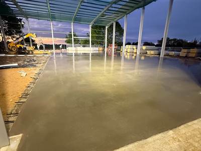 Completed power-floated floor slab inside the steel-framed building at dusk